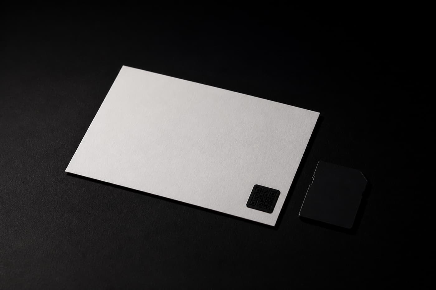 뒤집힌 인화 사진의 흰 뒷면 모서리에 붙은 작은 QR 코드 스티커와 메모리 카드